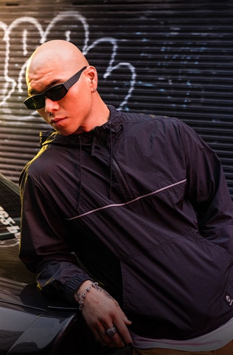 Man leaning on a car wearing a Timberland windbreaker.